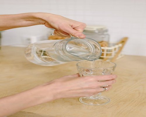 A close-up of hands pouring fresh clean water into a glass, highlighting simple daily hydration habits